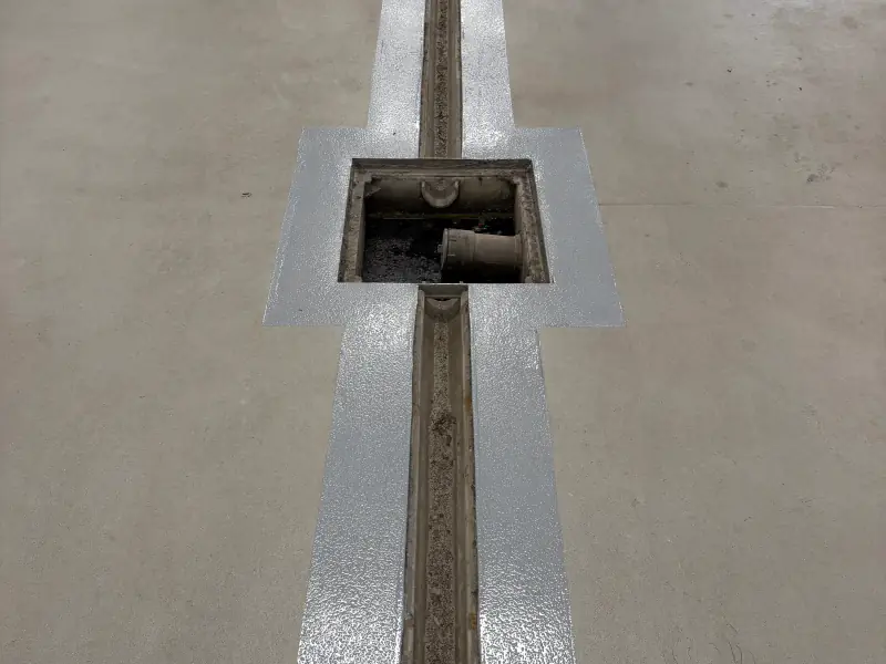 Trench drain and catch basin coated in grey epoxy in a commercial garage floor