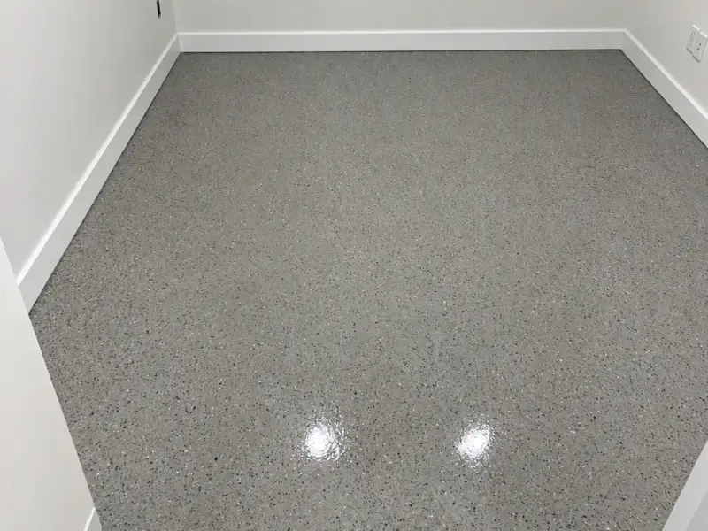 Petite pièce aux murs et plinthes blancs, plancher fini en époxy à flocons gris lustré