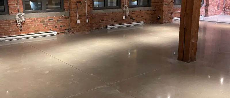 Plancher de béton poli lustré dans un loft à structure de bois et brique